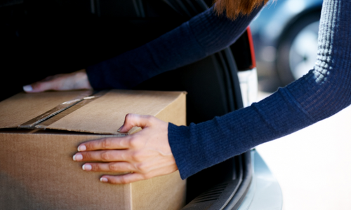 woman putting box in trunk